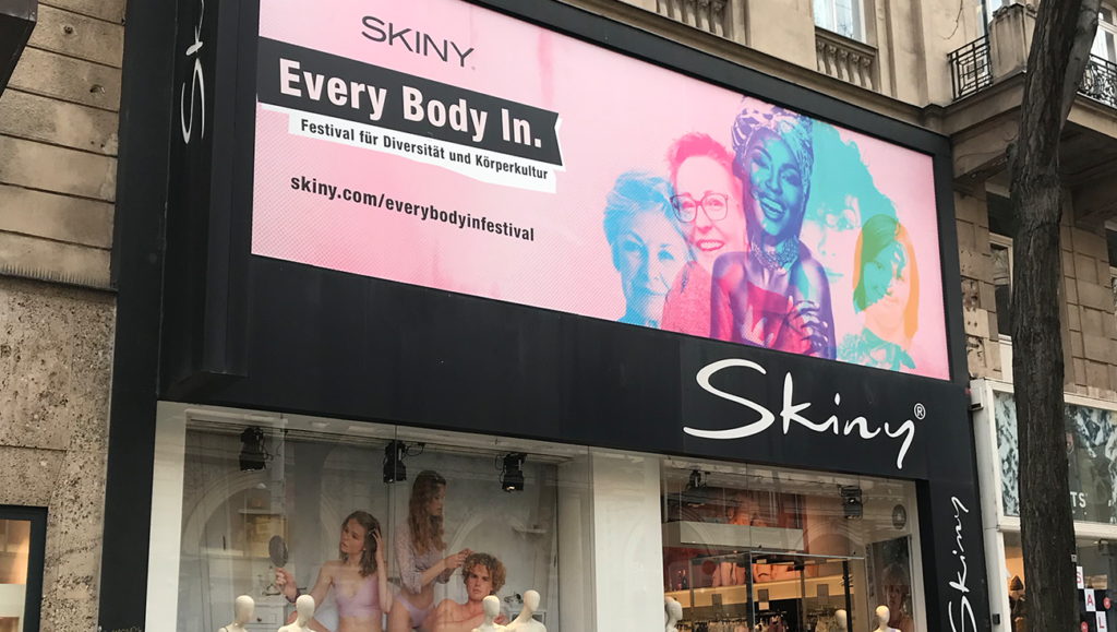 Auf dem Bild ist der SKINY Flagship-Store auf der Mariahilfer Straße zu sehen mit dem Every Body In. Festival-Sujet. 