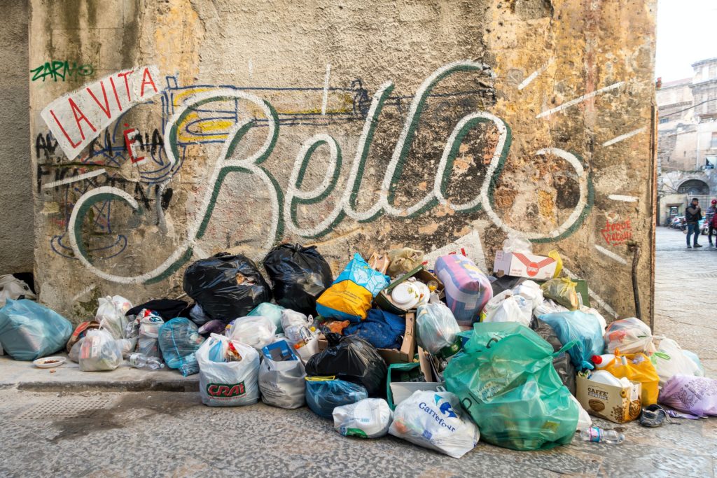 Auf diesem Bild sieht man einen Müllberg und im Hintergrund den Schritzug "La vita e bella"