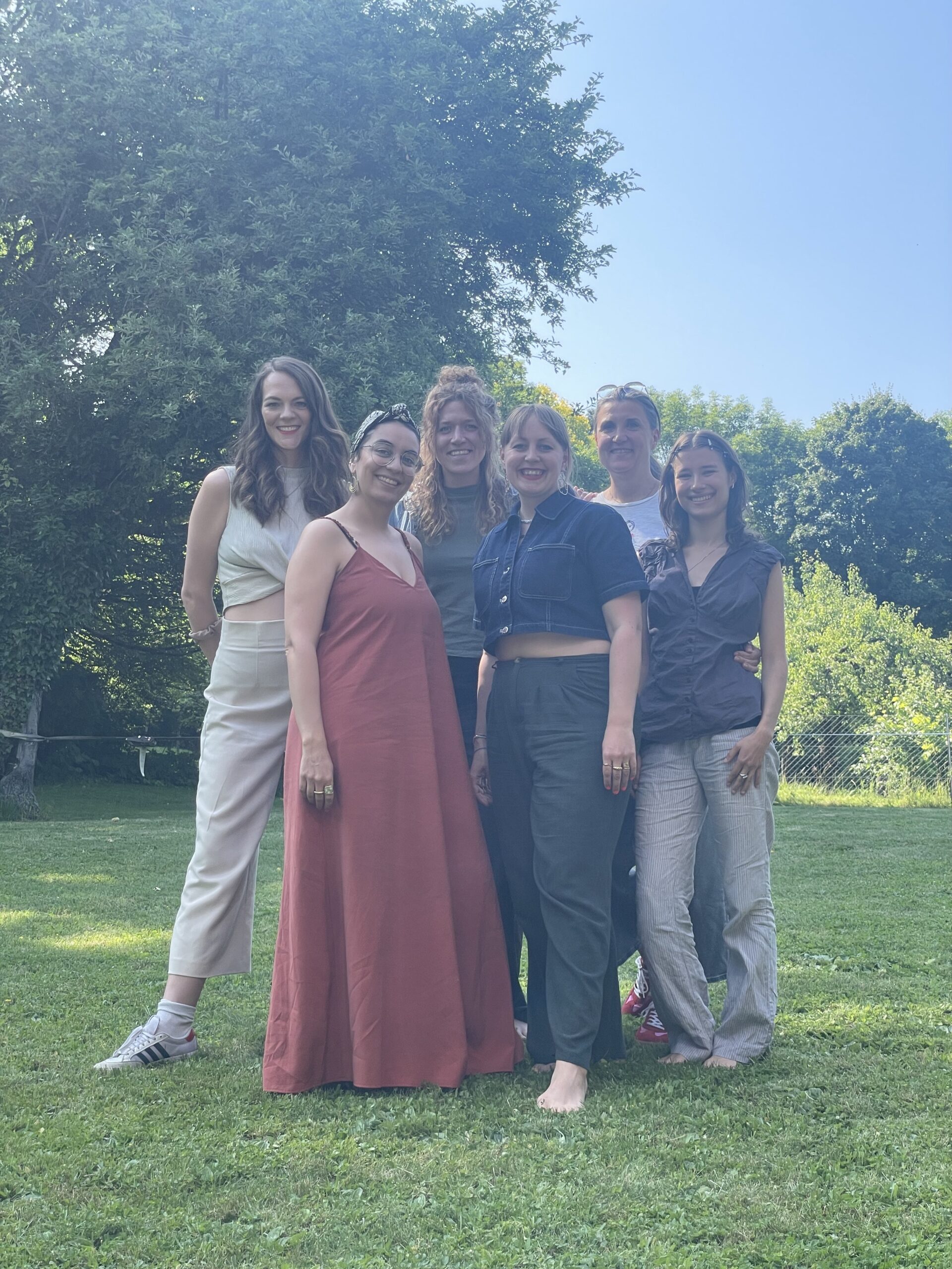 Das Team von Visionistas steht gemeinsam auf einer Wiese im Grünen